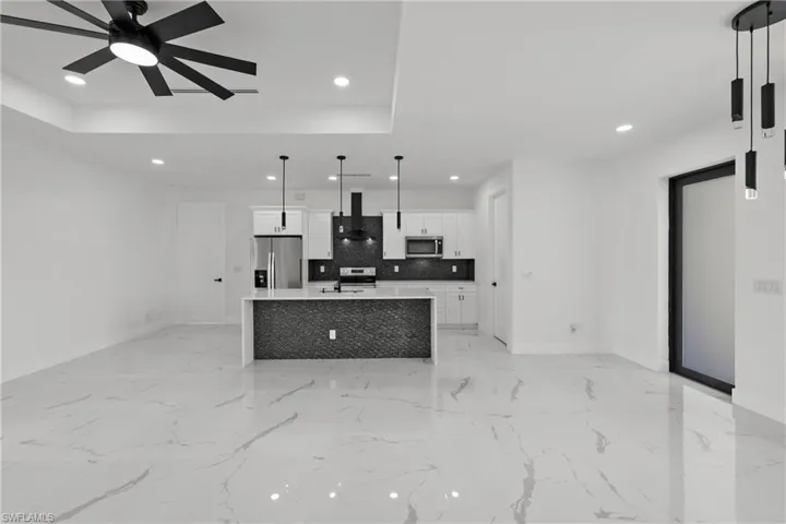 Kitchen featuring wall chimney range hood, stainless steel appliances, baseboards, and recessed lighting