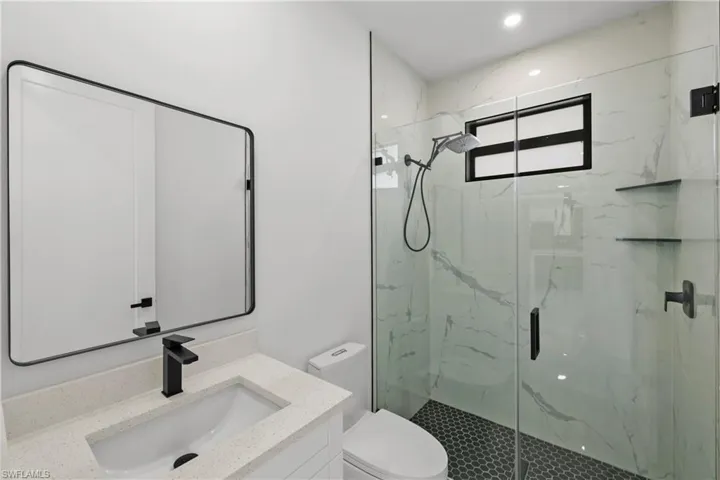 Bathroom featuring toilet, a marble finish shower, and vanity