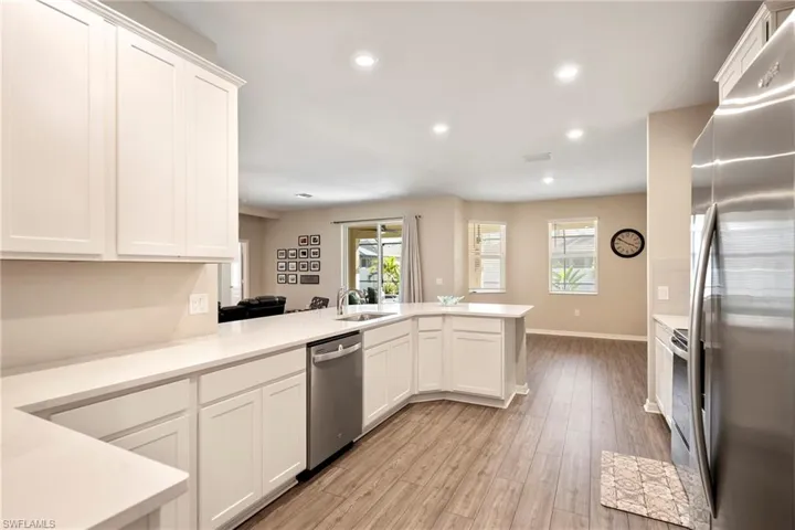 Kitchen featuring stainless steel appliances, a peninsula, white cabinetry, light wood finished floors, and recessed lighting