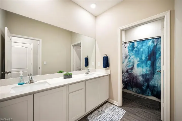 Full bath featuring double vanity, a shower with curtain, and light wood finished floors