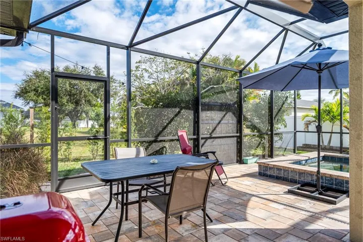 View of patio / terrace featuring a lanai, an in-ground hot tub, a sunroom, and outdoor dining space