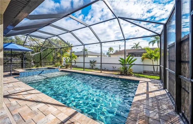 Integrated pool / hot tub featuring a sunroom, a lanai, a fenced backyard, and a patio area