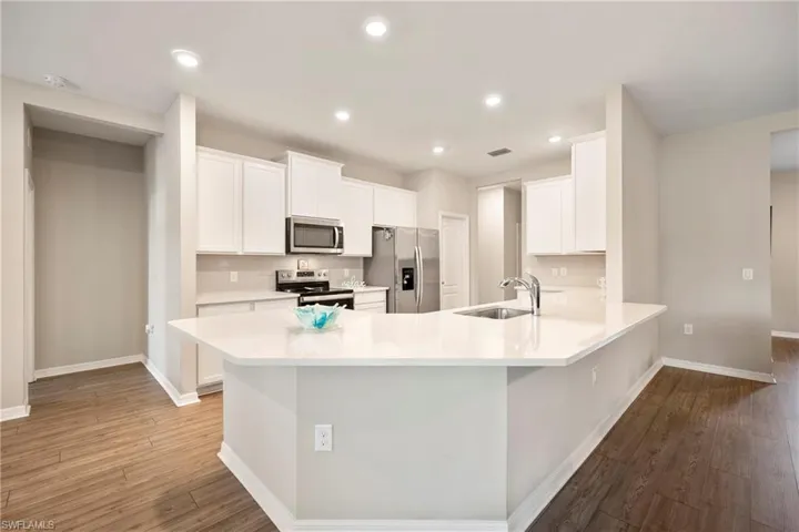 Kitchen featuring white cabinetry, stainless steel appliances, recessed lighting, light wood-type flooring, and a peninsula