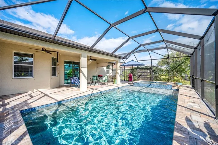 Relaxing pool / spa featuring a sunroom, a patio, and glass enclosure