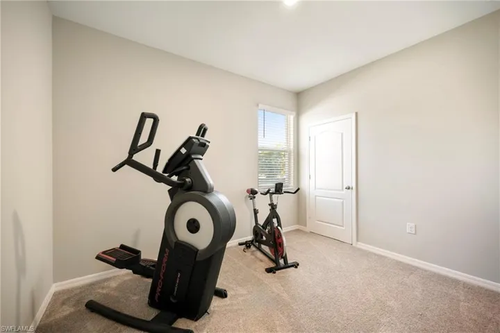 Exercise room with carpet flooring and baseboards