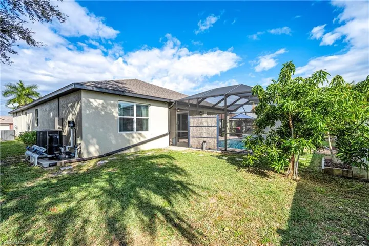Back of house featuring a sunroom, a lanai, a yard, a swimming pool, and stucco siding