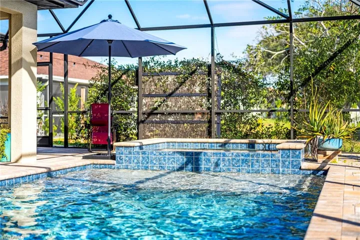 Outdoor pool featuring glass enclosure, a sunroom, and a hot tub