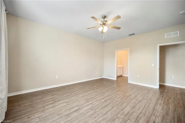 Unfurnished bedroom with a ceiling fan, light wood finished floors, and connected bathroom