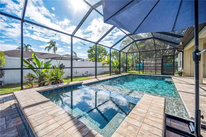Integrated pool / hot tub featuring a fenced backyard, a sunroom, glass enclosure, and a patio