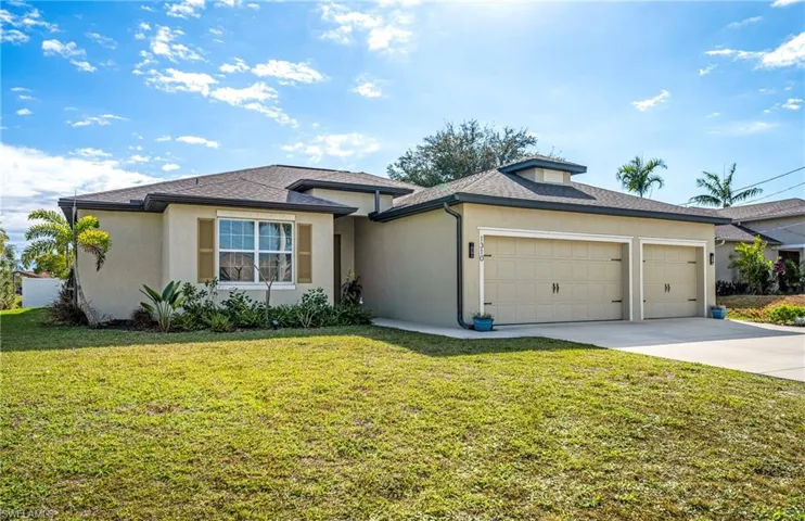 View of front of house featuring a front yard, stucco siding, and a garage