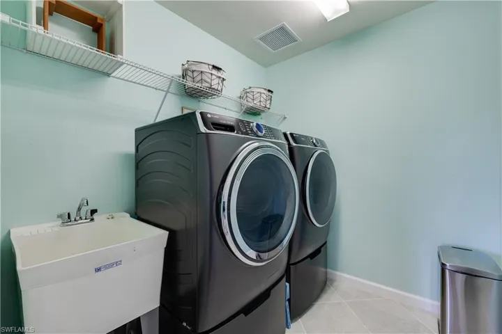 Washroom with tile patterned flooring and washer and clothes dryer