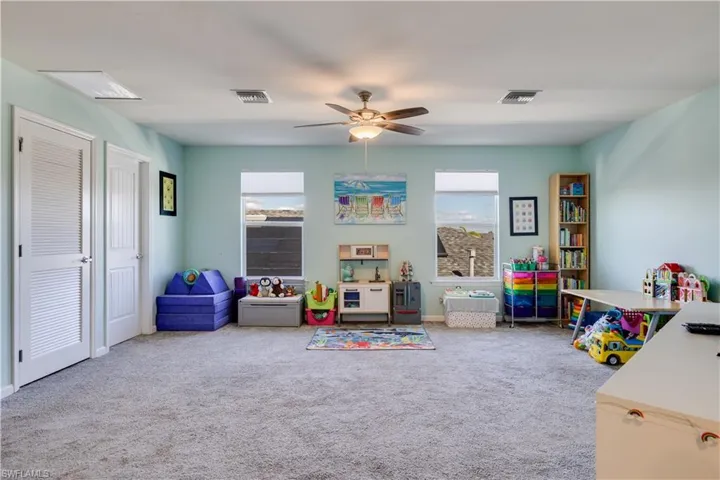Loft with light colored carpet and a ceiling fan