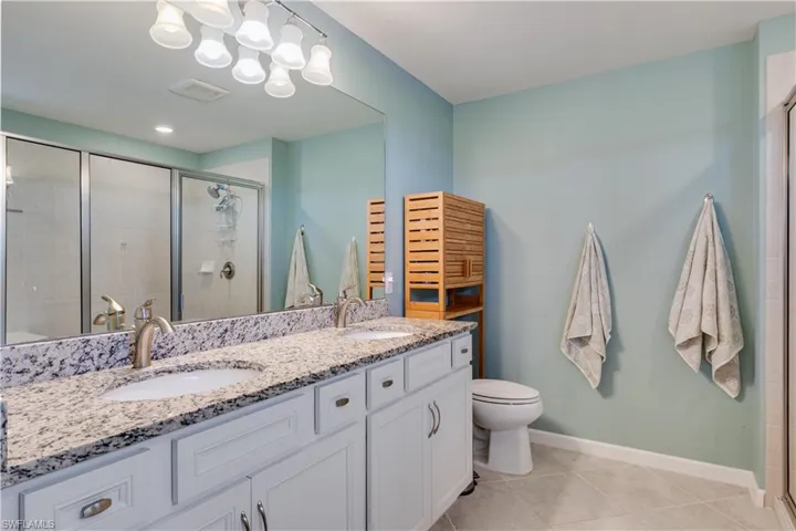 Full bath featuring a shower stall, double vanity, and light tile patterned floors