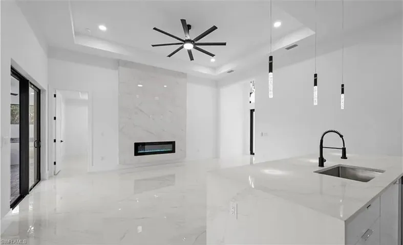 Unfurnished living room featuring a tray ceiling, a premium fireplace, a ceiling fan, and light marble finish flooring