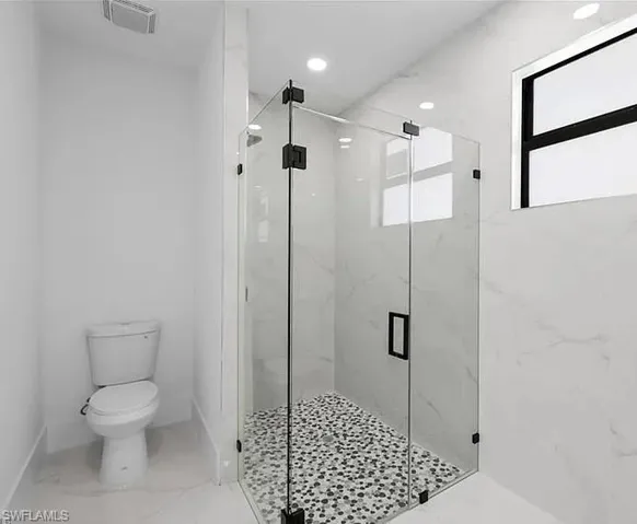 Bathroom with a marble finish shower, marble finish floors, and recessed lighting