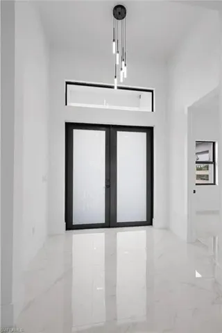 Foyer entrance featuring light marble finish floors and french doors