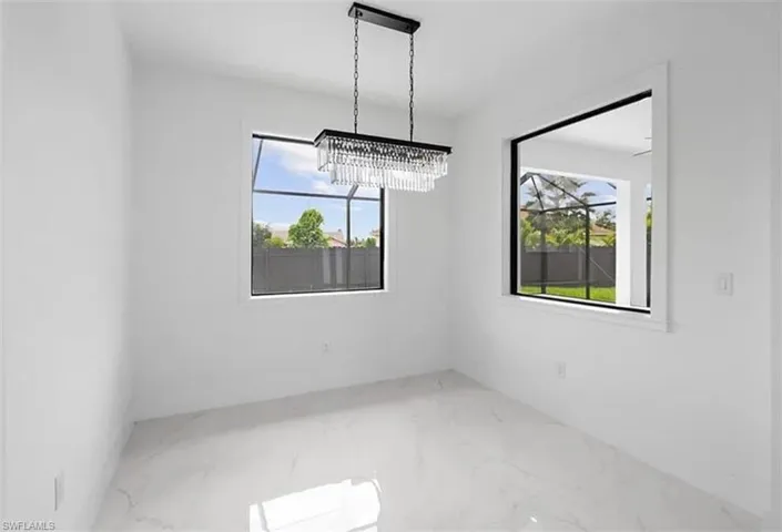 Unfurnished dining area featuring marble finish flooring and a chandelier