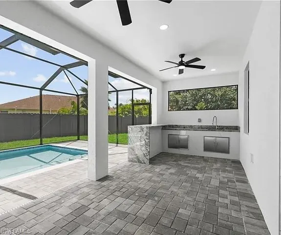 View of patio / terrace featuring ceiling fan, an outdoor kitchen, a sunroom, and glass enclosure