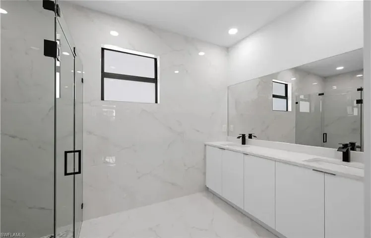Bathroom with plenty of natural light, a marble finish shower, double vanity, and recessed lighting