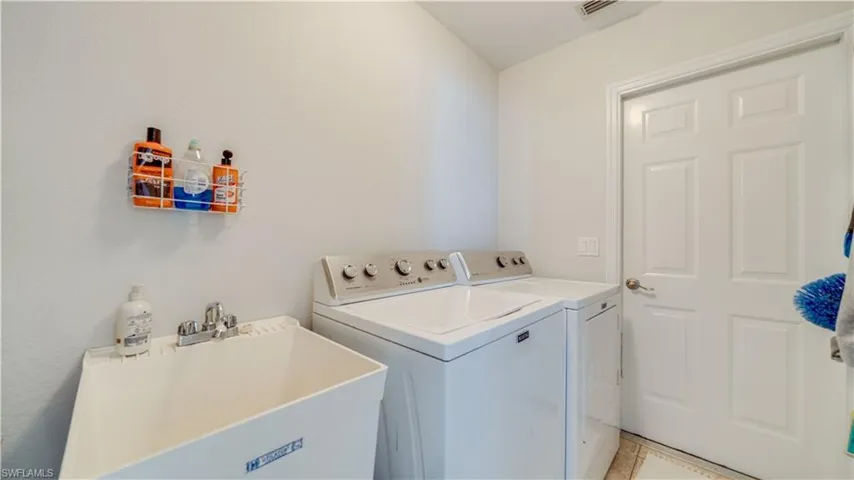 Laundry room with a sink, visible vents, washing machine and dryer, and laundry area