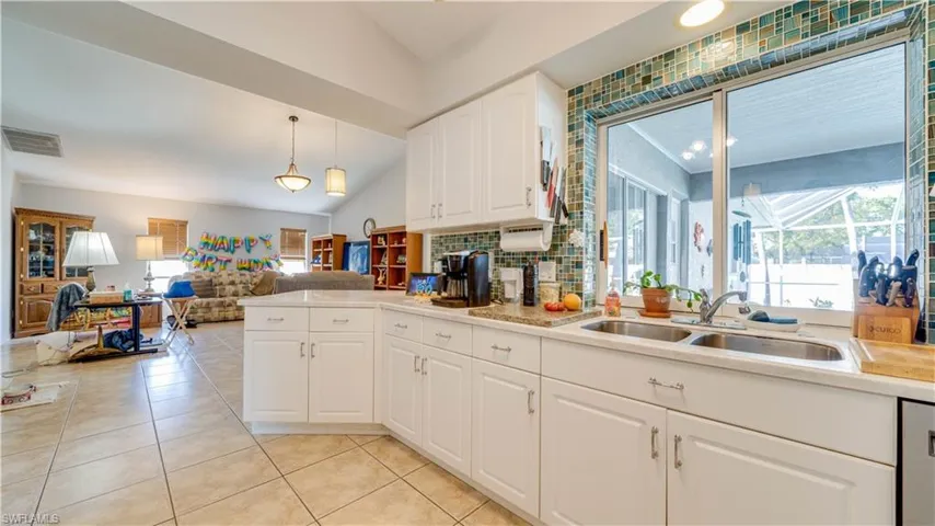 Kitchen featuring light tile patterned floors, visible vents, a sink, light countertops, and white cabinetry