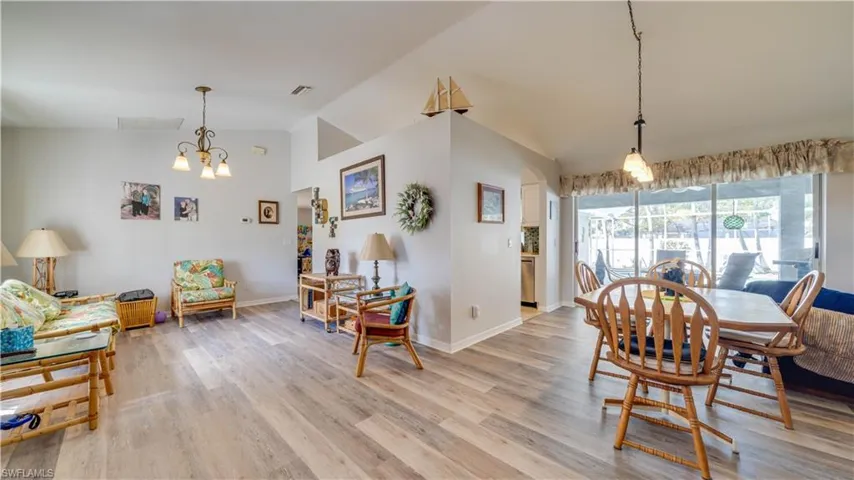 Dining space featuring visible vents, light wood finished floors, a notable chandelier, and vaulted ceiling