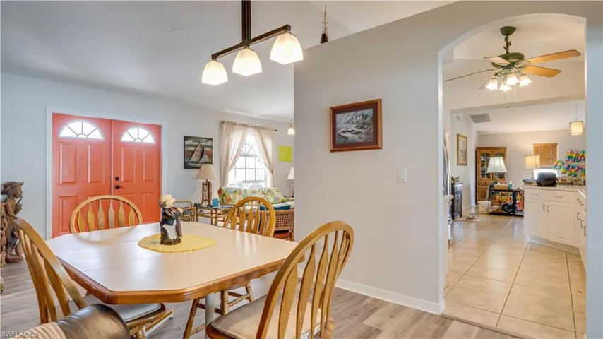 Dining room with visible vents, baseboards, light wood-type flooring, arched walkways, and a ceiling fan