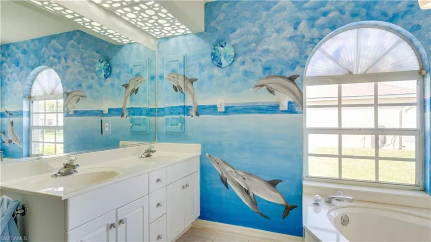 Full bathroom with double vanity, wallpapered walls, and a sink