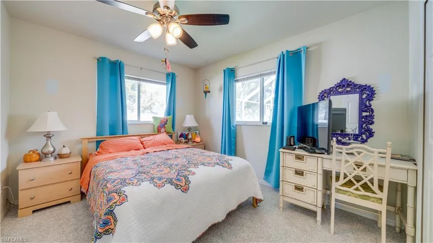 Carpeted bedroom with multiple windows and ceiling fan