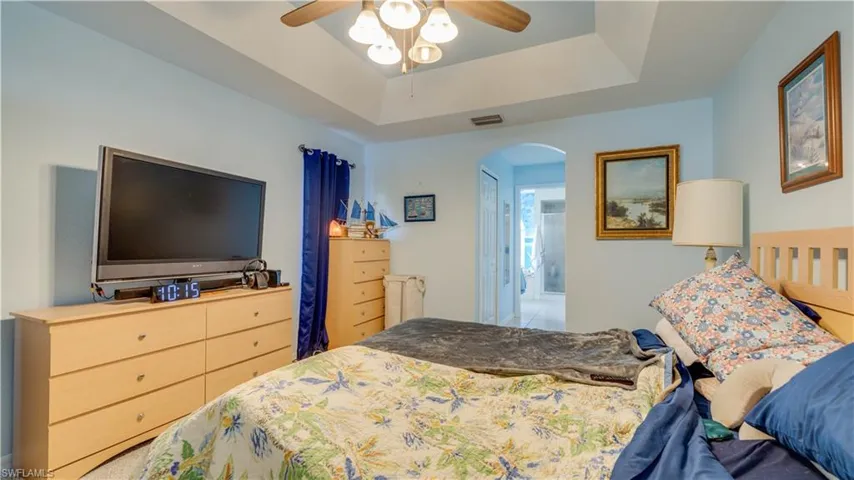 Bedroom featuring visible vents, arched walkways, a raised ceiling, and ceiling fan
