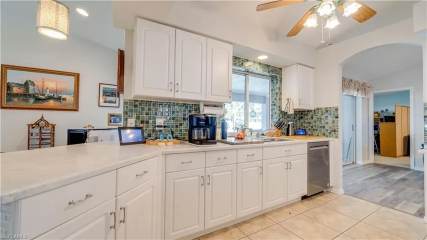 Kitchen with light countertops, tasteful backsplash, a ceiling fan, and arched walkways