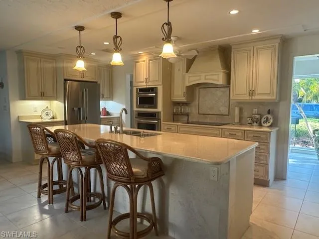 Kitchen with decorative light fixtures, light tile patterned flooring, stainless steel refrigerator with ice dispenser, recessed lighting, and custom range hood