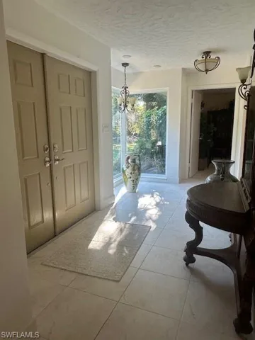 Foyer with a textured ceiling, a chandelier, and light tile patterned flooring