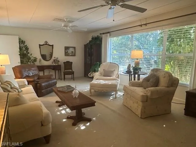 Carpeted living area featuring ceiling fan