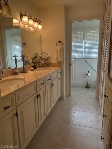 Bathroom with a closet, double vanity, and light tile patterned floors
