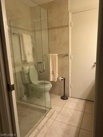 Bathroom featuring tile patterned floors, a stall shower, and tile walls