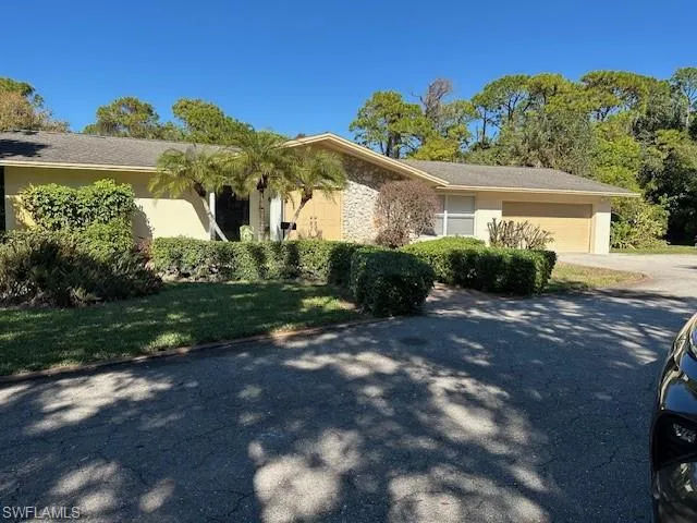 View of home's exterior with an attached garage, driveway, stucco siding, and stone siding