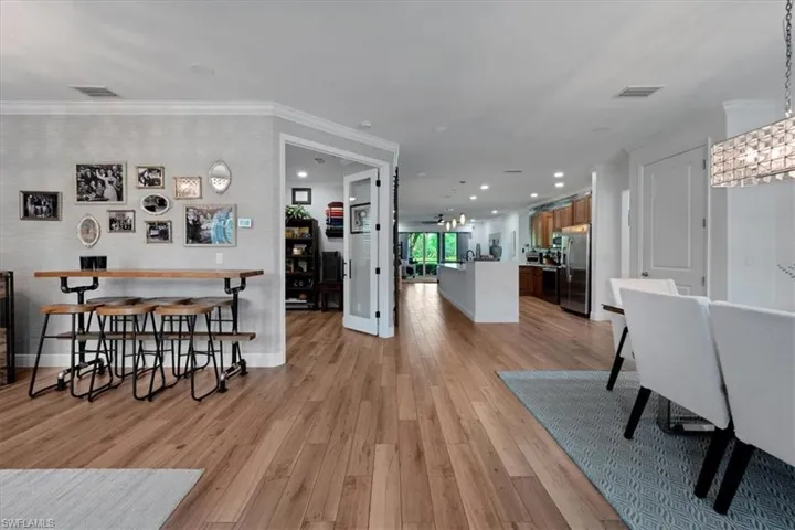 Wood-finish flooring throughout, with a crystal chandelier, recessed lighting, and a kitchen island with seating