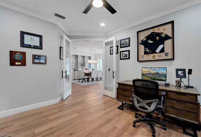Wood-finish flooring, crown molding, and a ceiling fan