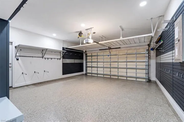 Epoxy flooring, overhead storage racks, garage door, wall-mounted storage panels, and recessed lighting