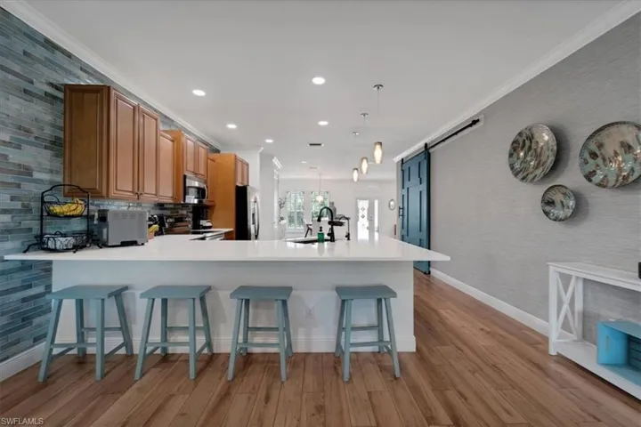 Kitchen island with white countertop, wood-finish flooring, wood cabinetry, and a full-height tile backsplash