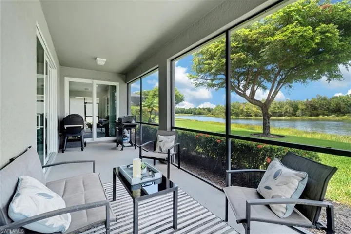 Screened patio with concrete flooring, multiple sliding glass doors, and a serene water backdrop
