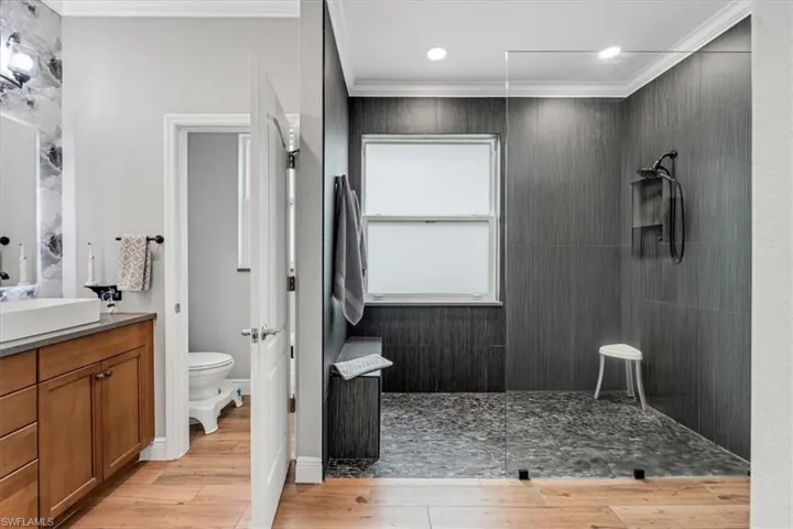 Walk-in shower with dark tile surround, integrated bench seating, and a window