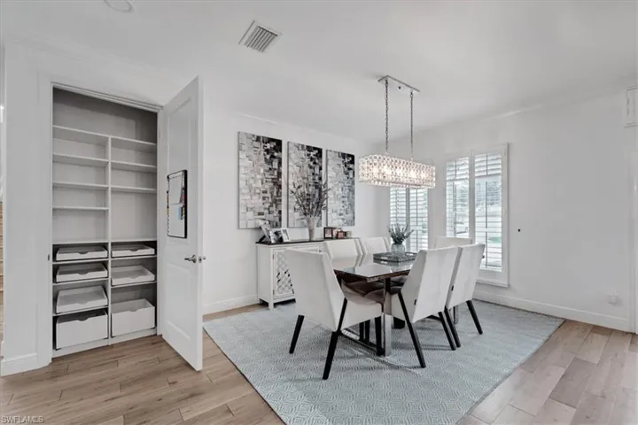 Recessed lighting, crown molding, a built-in storage closet, a crystal-detail linear chandelier, and wood-finish flooring