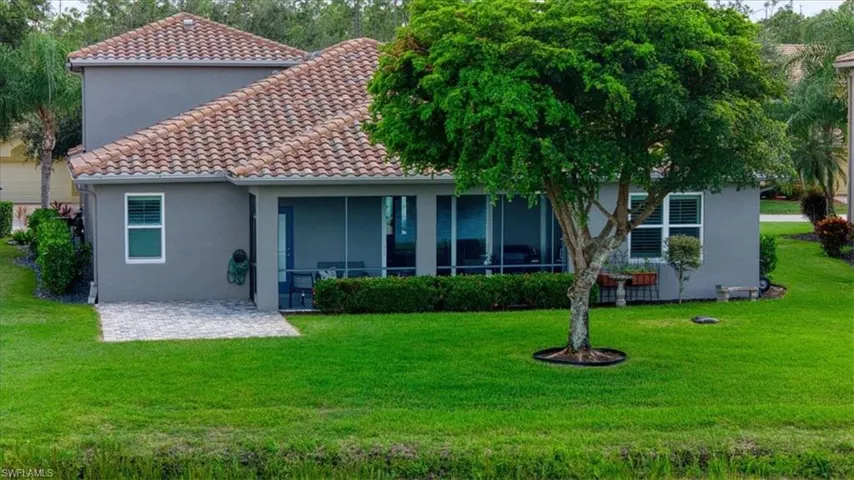 Stucco exterior with a tile roof, featuring a screened patio and a paver patio