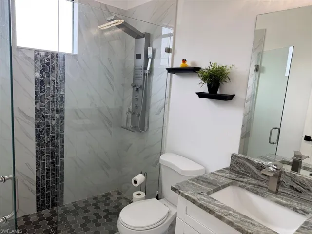 Bathroom featuring vanity and a marble finish shower