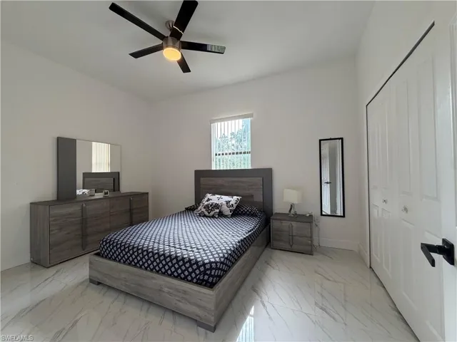 Bedroom featuring marble finish flooring, a closet, and a ceiling fan