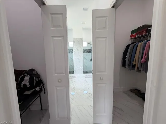 Walk in closet featuring light marble finish floors
