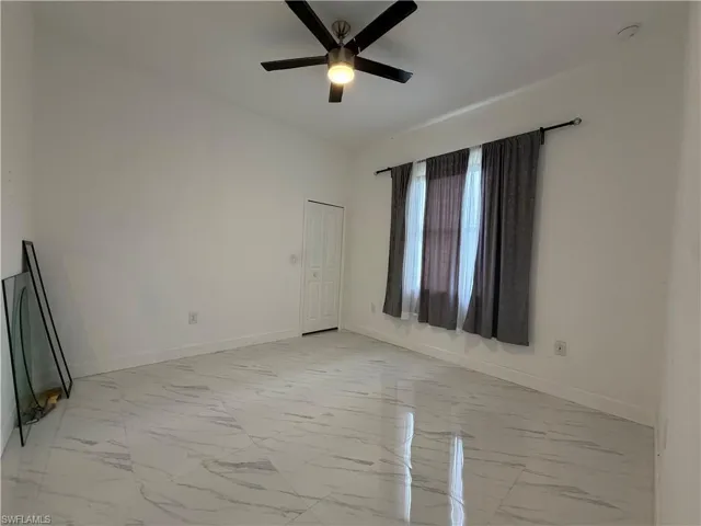 Spare room featuring light marble finish flooring and a ceiling fan
