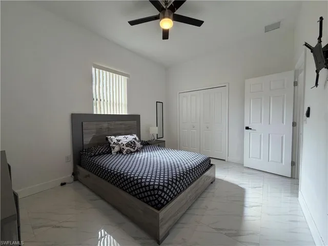 Bedroom featuring light marble finish floors, ceiling fan, and a closet